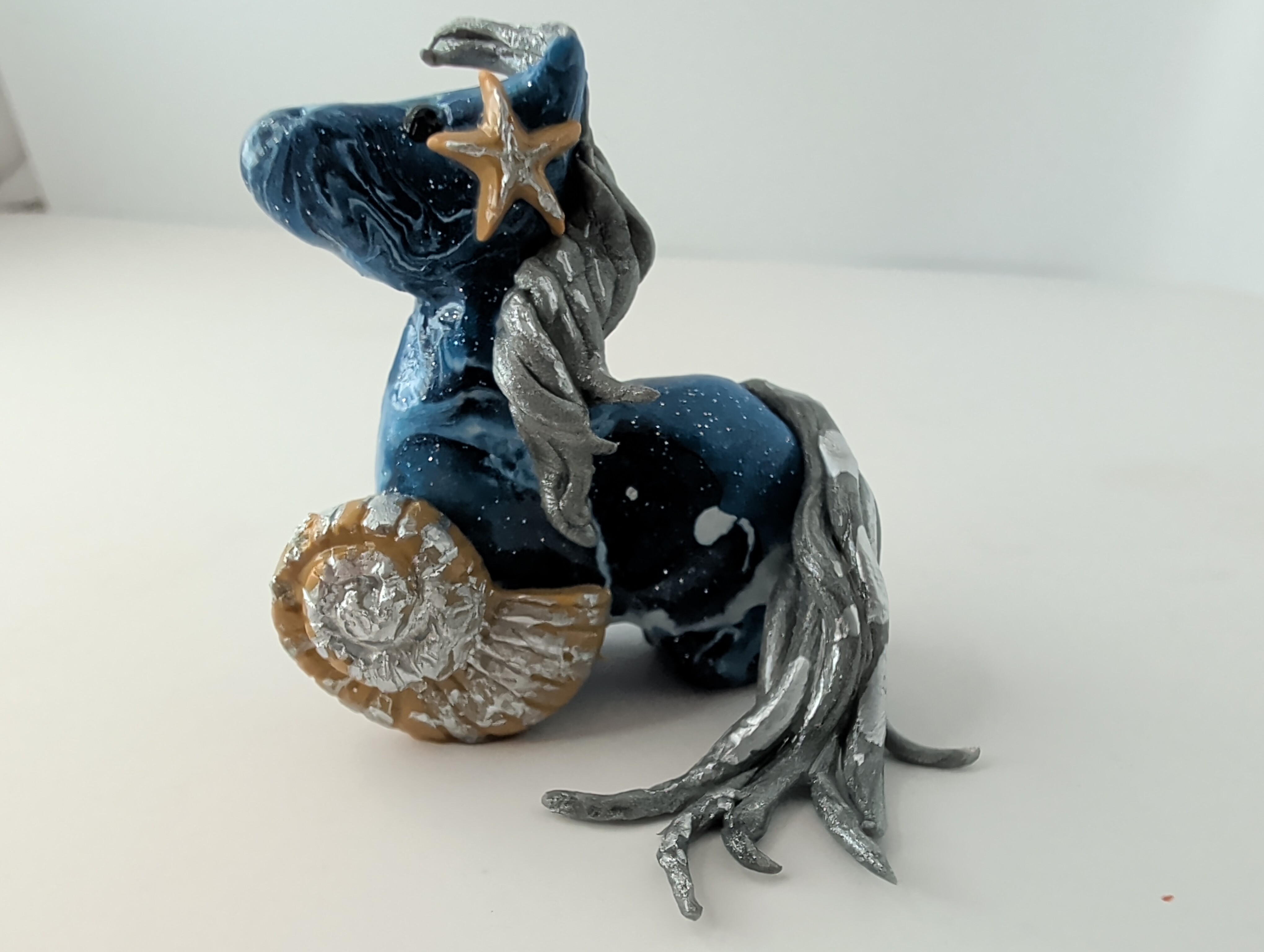 Ocean blue horse figurine with a silver mane, starfish, and shell